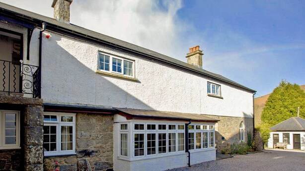 A two-story building with a white exterior, stone foundation, and multiple windows. - 2 bedroom accommodation in Widecombe-in-the-Moor, near Bovey Tracey (Widecombe-in-the-Moor, near Bovey Tracey)