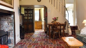 A dining area with a patterned carpet, wooden table, chairs, and a fireplace. - 2 bedroom accommodation in Widecombe-in-the-Moor, near Bovey Tracey (Widecombe-in-the-Moor, near Bovey Tracey)