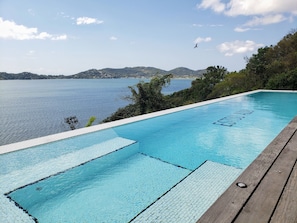 A rectangular swimming pool with clear blue water, surrounded by a wooden deck.