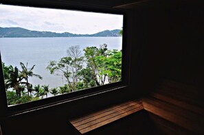 A room with a large window overlooking a body of water and greenery.