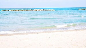 På stranden, hvit sand, solsenger og parasoller