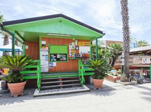 A small, green-roofed building with a wooden facade, steps leading up to a green door, and potted plants around. - Villaggio Camping Duca Amedeo (Martinsicuro)