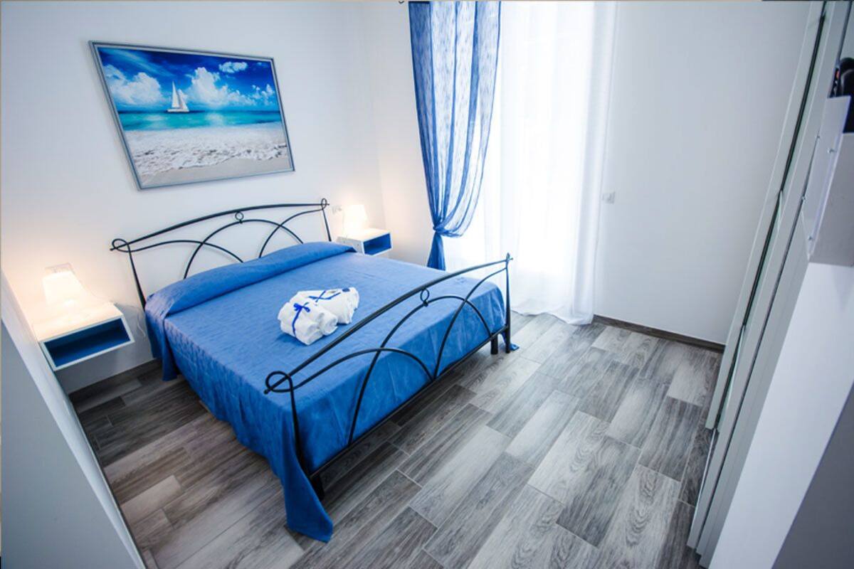 A neatly arranged bedroom with a bed, a nightstand, a wall-mounted picture, and a window with curtains.