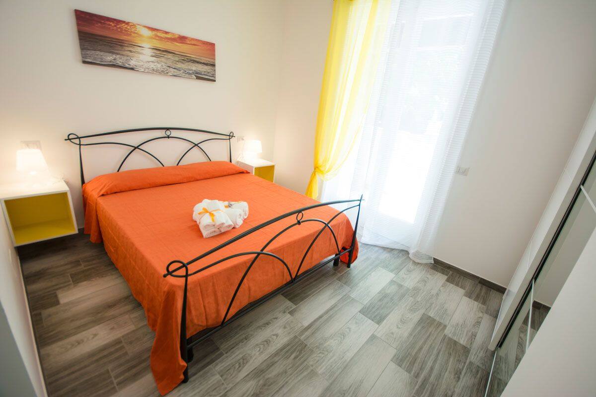 A bedroom with a bed, bedside tables, a painting, and a window with curtains.