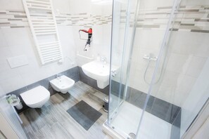 Un baño moderno con cabina de ducha de vidrio, inodoro, bidé y lavamanos.