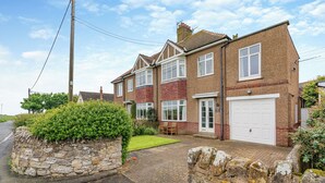 A two-story house with a stone wall, a garage, and a well-maintained lawn.