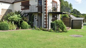 A two-story house with a balcony, a stone wall, and a well-maintained garden. - 1 bedroom accommodation in Sidbury, near Sidmouth (Sidbury, near Sidmouth)
