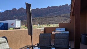 A patio with a glass table and chairs, a grill, and a view of mountains. - Slickrock Sands - Sleeps 8! Pet/bike friendly. (Moab)