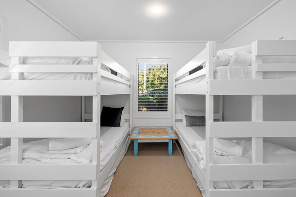 A bunk bed room with a small table and a window with blinds. - Fern - Ocean Views, Middle Of Town Pet Friendly (Lorne)