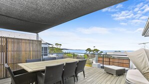 Une terrasse avec une table et des chaises, donnant sur un plan d’eau.