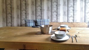 Una mesa de madera con una olla de metal, tazones, una cuchara y una rebanada de pan.
