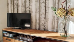 Un mueble de madera con centro de entretenimiento, un televisor de pantalla plana, un jarrón de cristal con flores y un reproductor de DVD.