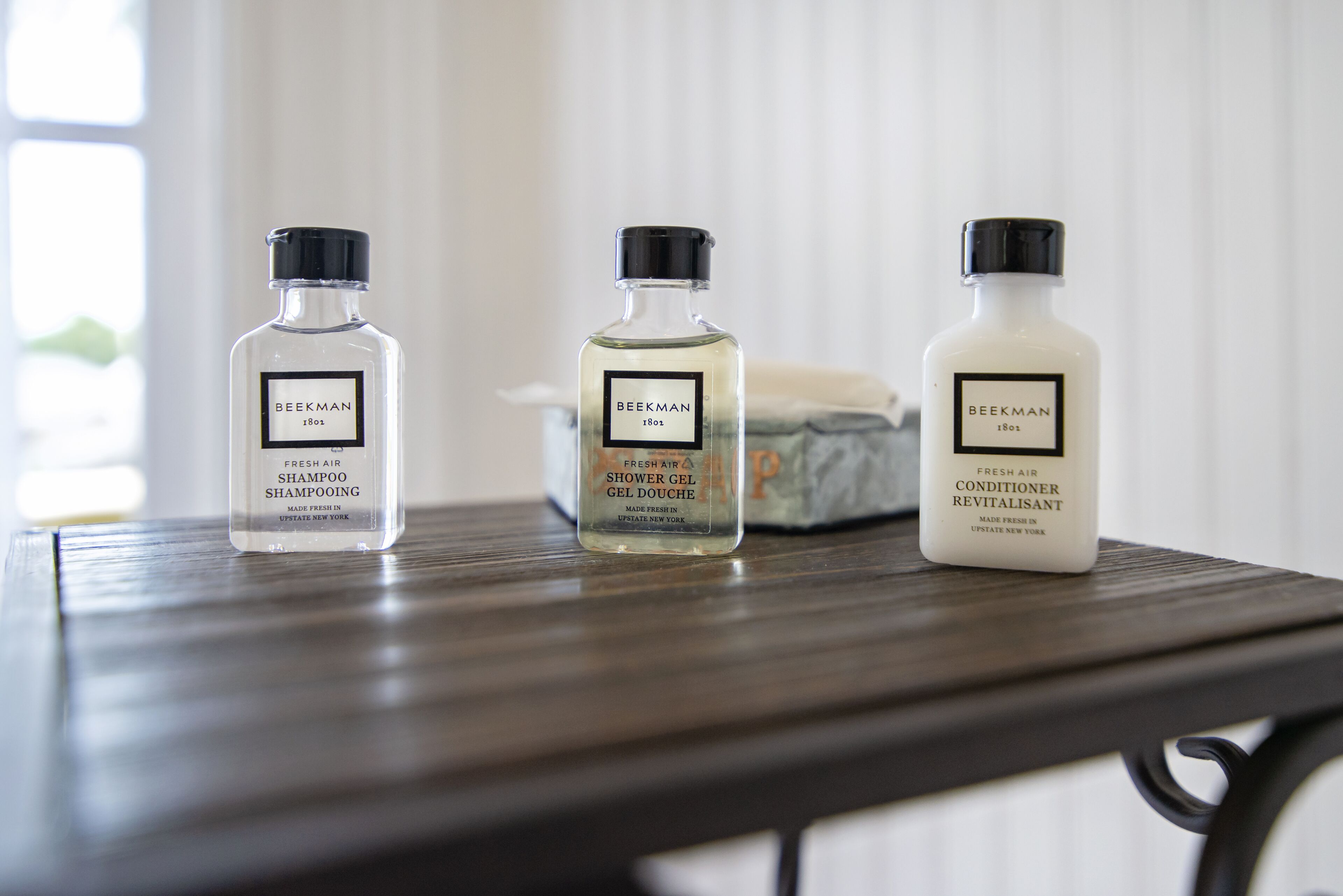 Three bottles of Beekman Fresh Air products on a wooden table.