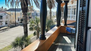 A balcony with wooden railings, palm trees, and a view of residential buildings.