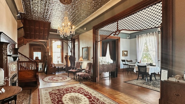 A spacious living room with a grand staircase, wooden flooring, and a chandelier.