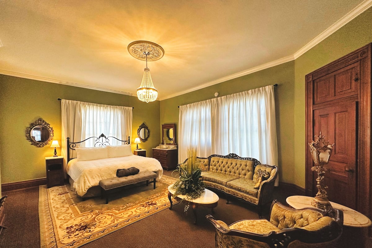Une chambre traditionnelle avec un lit, un canapé, un fauteuil et un lustre.