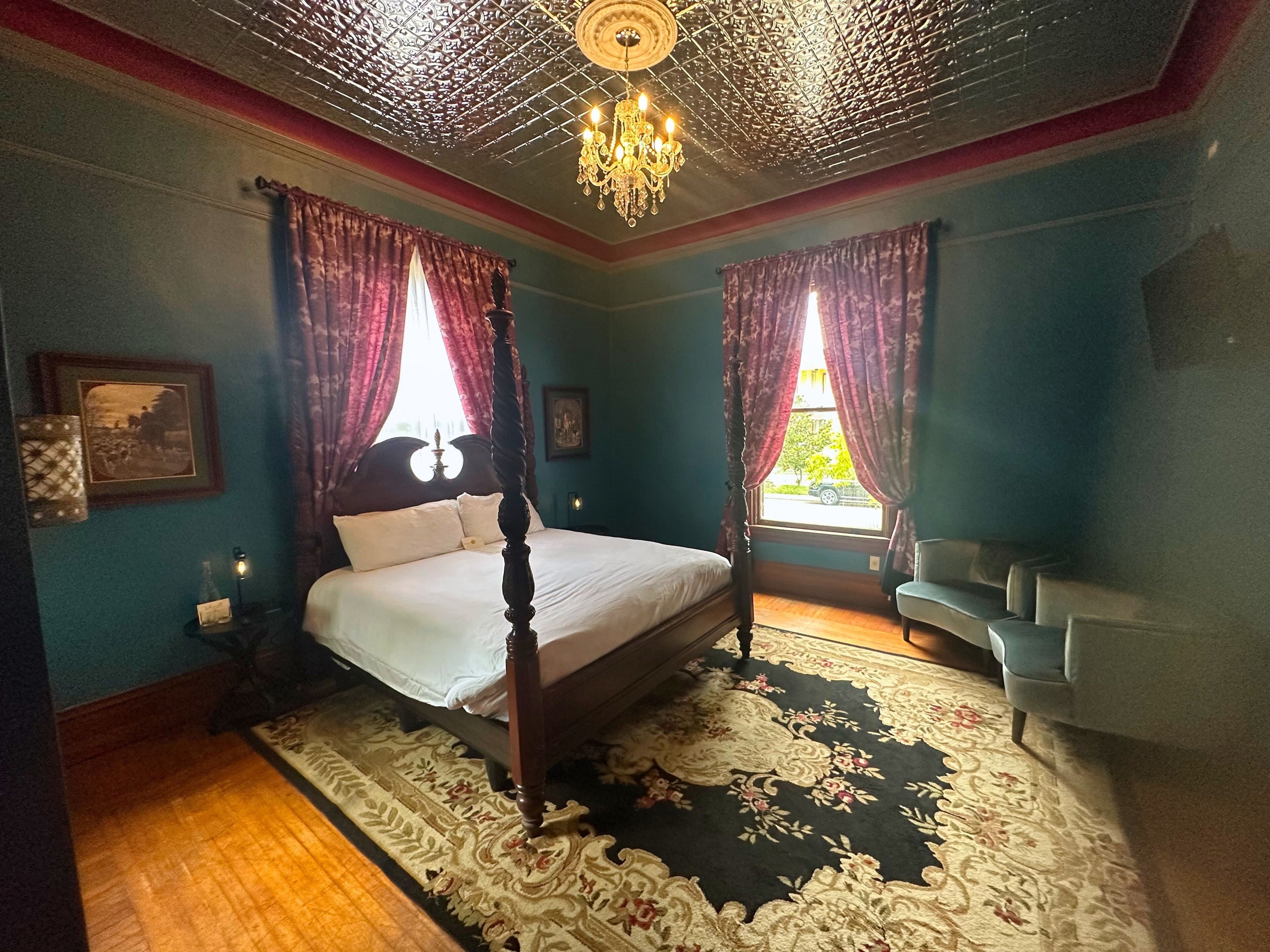 Un lit à baldaquin, un lustre et un tapis à motifs floraux.