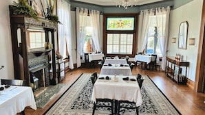 A dining area with multiple tables set for service, a fireplace, and a stained glass window.
