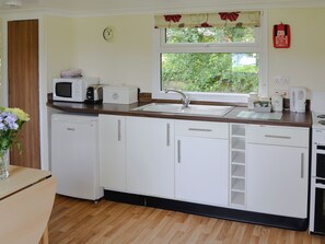 A modern kitchen with white cabinets, a microwave, a toaster, and a sink. - White Moth - UK12697 (Stalham)