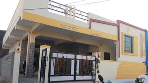 A building with a yellow and white facade, a gated entrance, and a motorcycle parked in front.