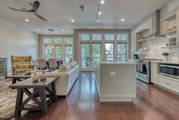 A spacious kitchen with a central island, large windows, and a dining area with a sofa and chairs.