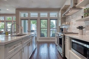 A modern kitchen with a central island, built-in oven, and large windows.