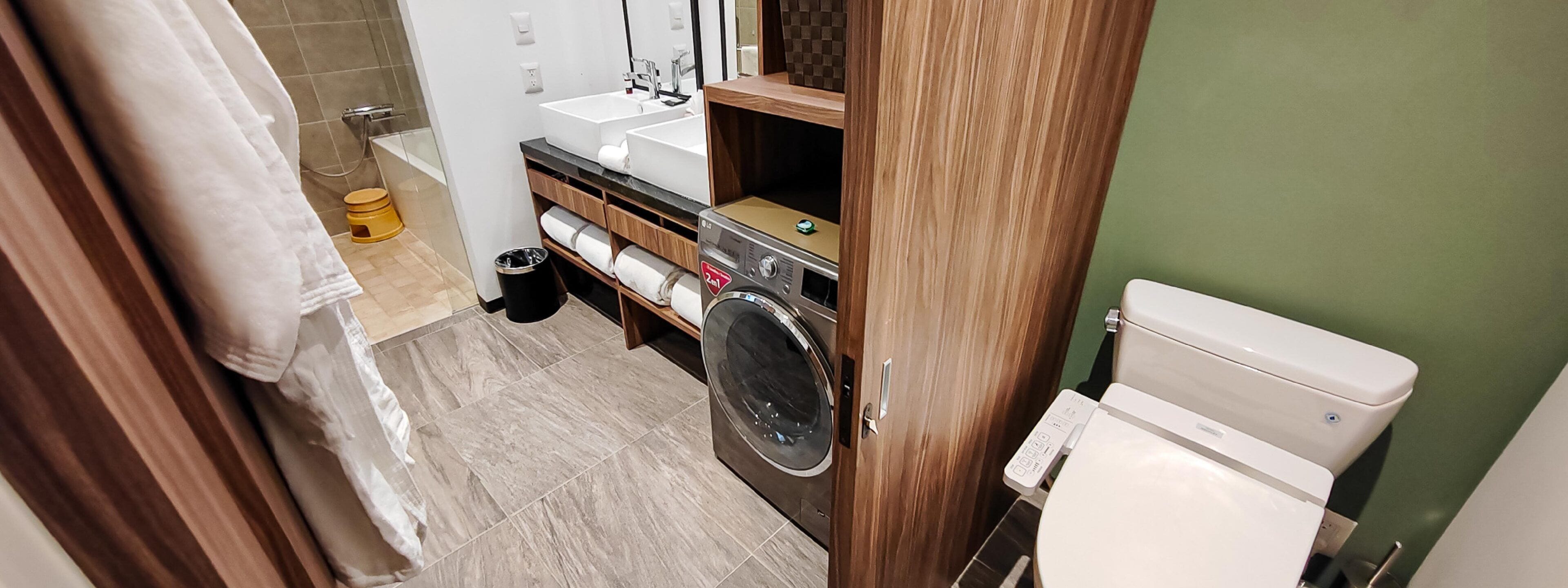 Une salle de bain équipée de toilettes, d’un lave-linge et d’un lavabo.
