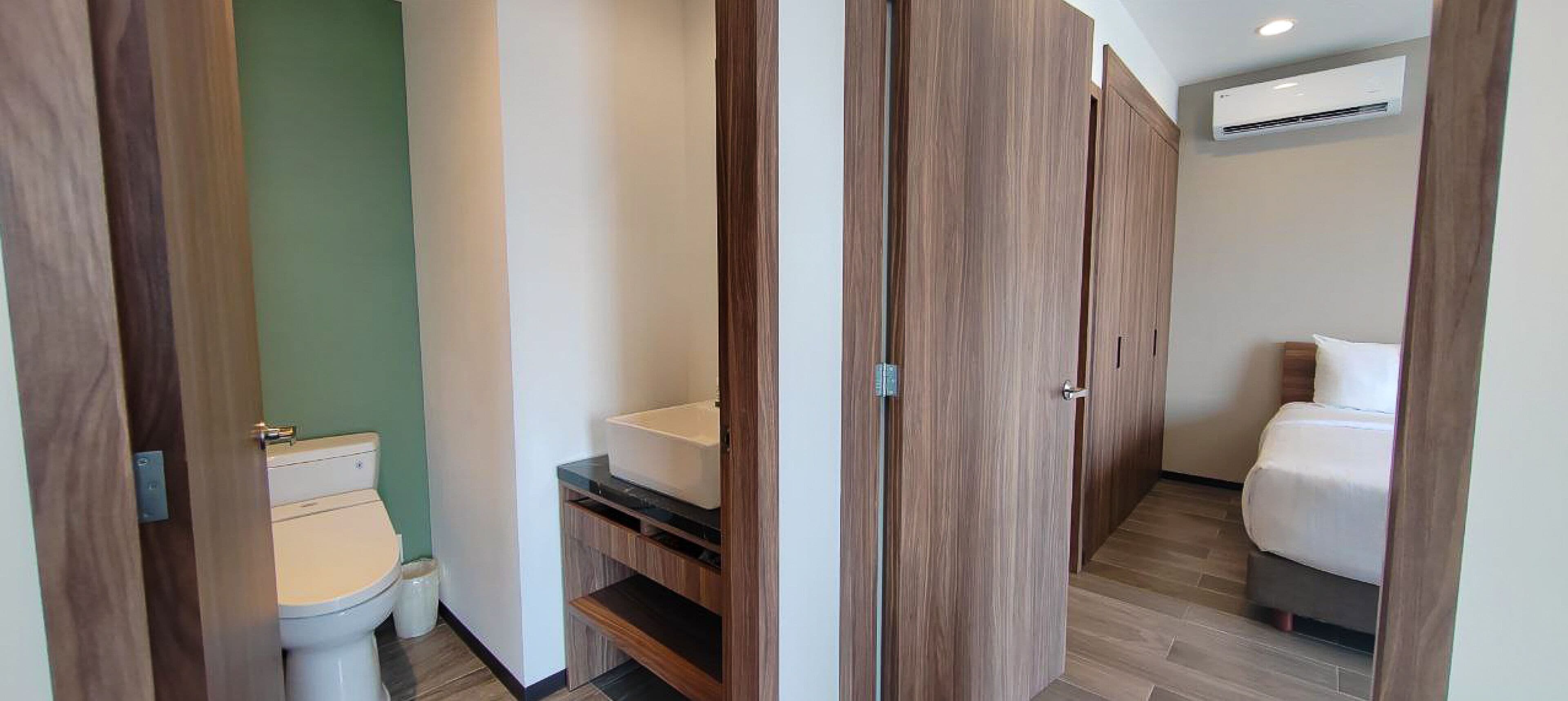 Habitació d'hotel amb un armari de fusta, un vàter, un lavabo i un llit.