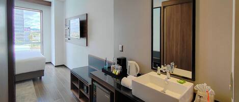 Un baño moderno con un lavamanos grande, un espejo y un televisor montado en la pared.