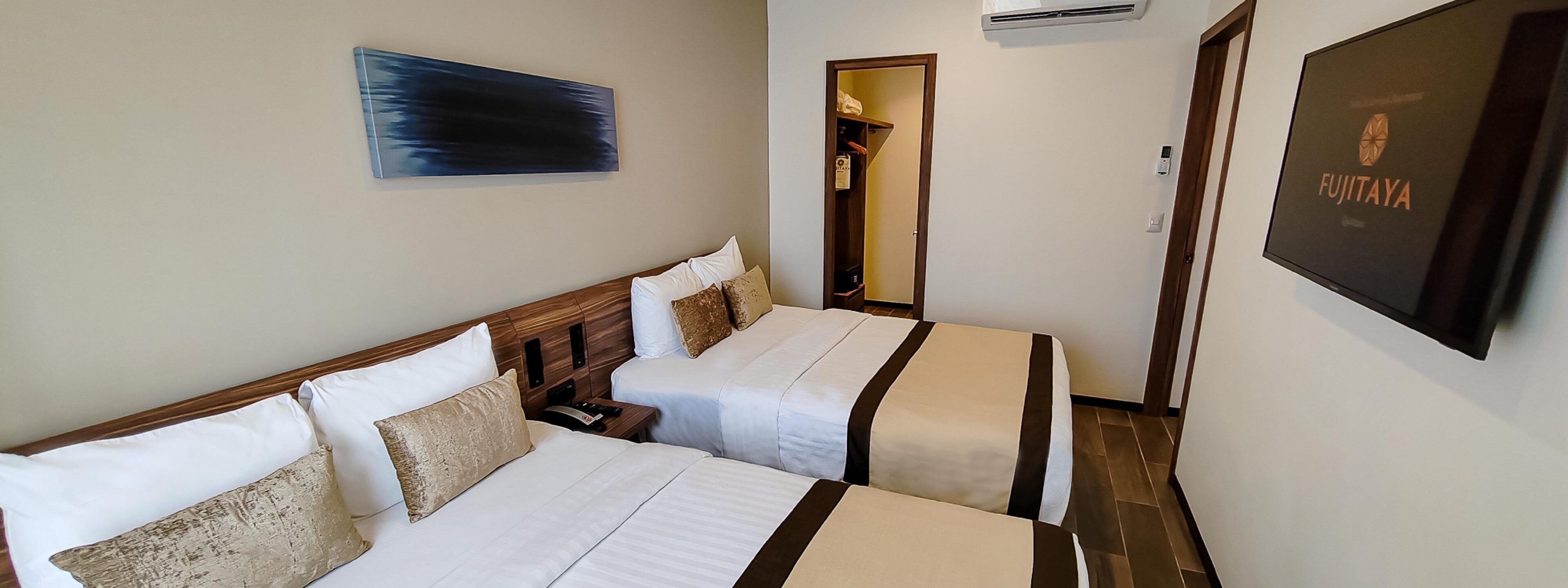 A hotel room with two beds, a painting on the wall, an air conditioning unit, and a framed sign on the wall.