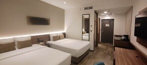 Une chambre d’hôtel avec deux lits, un bureau, une télévision et un miroir.