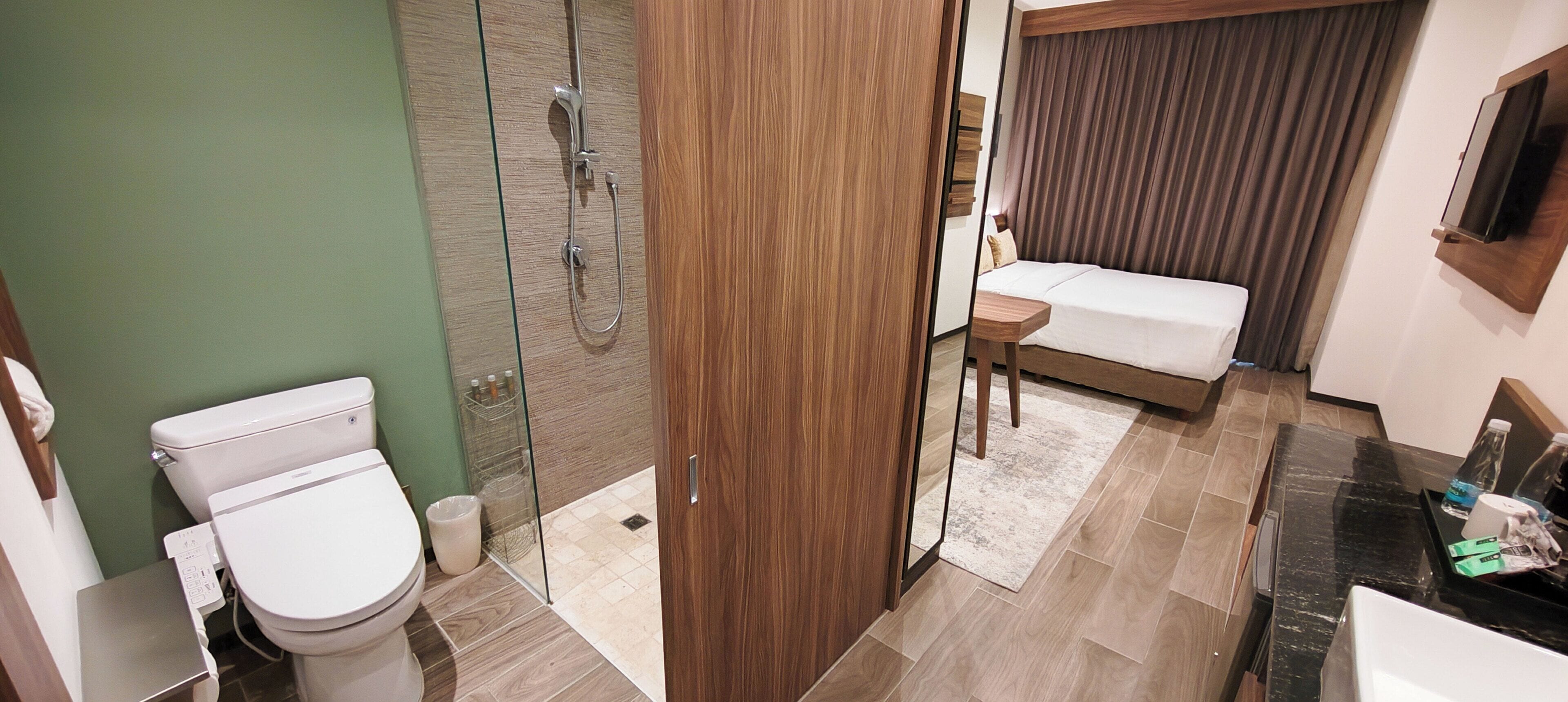 Un baño moderno con inodoro, ducha y una mesita de noche con televisor.