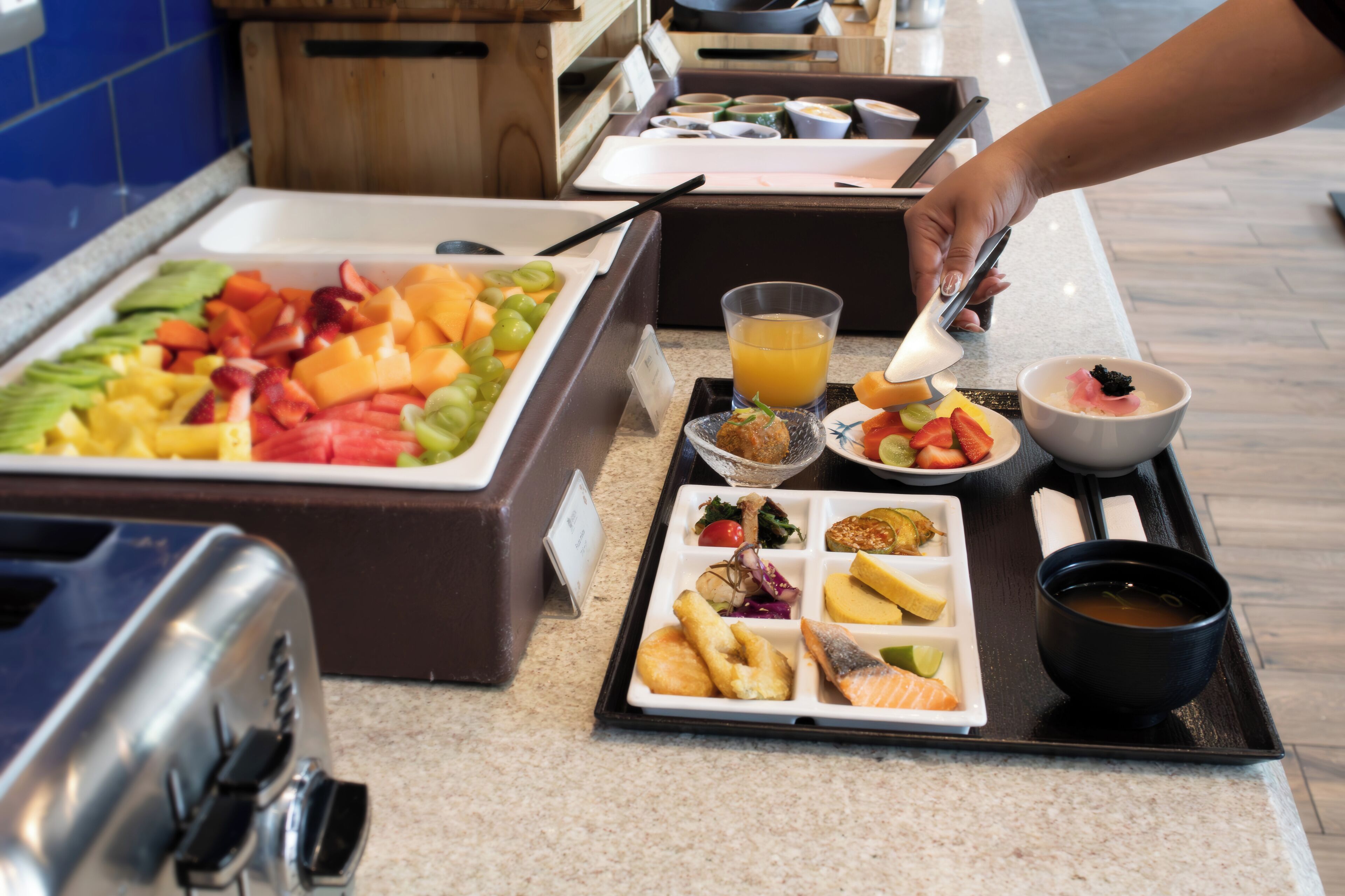 A buffet with various food items including fruits, vegetables, and a bowl of soup.