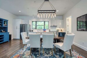A modern kitchen with white cabinets, a large window, and a dining area with a rug and chairs.