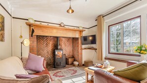 Ein gemütliches Wohnzimmer mit Kamin, Ledersofas, einem Flachbildfernseher und einem großen Fenster mit Aussicht.