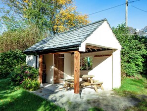 Un petit bâtiment d’un seul étage, doté d’un toit en pente, d’une porte en bois et d’un plancher en béton.