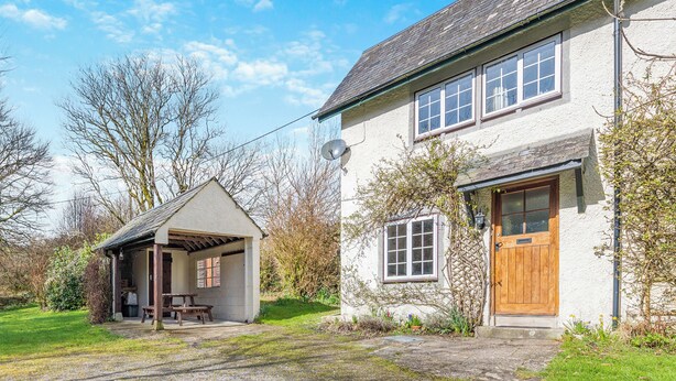 Ein zweistöckiges Haus mit einer Veranda und einer Holztür.
