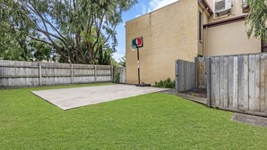 A backyard with a basketball hoop, a wooden fence, and a concrete patio. - Perfect for your beach holiday, you are only a stone's throw to the Port Fairy East Beach (Port Fairy)