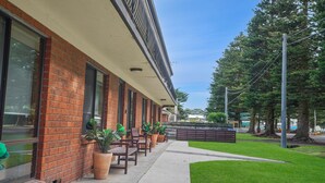 A building with a brick facade, large windows, outdoor seating with tables and chairs, and potted plants. - Perfect for your beach holiday, you are only a stone's throw to the Port Fairy East Beach (Port Fairy)