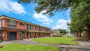 Un immeuble de deux étages doté d’un balcon, d’une enseigne indiquant la présence de logements de vacances et d’une pelouse bien entretenue.