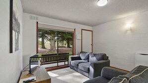 A modern living room with a grey sofa, a wooden coffee table, and a TV. - Perfect for your beach holiday, you are only a stone's throw to the Port Fairy East Beach (Port Fairy)