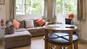 Un salon chaleureux avec un canapé, une table ronde en bois et un vase avec une fleur.