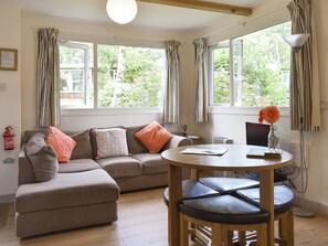 A cozy living room with a sofa, a round wooden table, and a vase with a flower. - 2 bedroom accommodation in Mount Hawke, near Redruth (Mount Hawke, near Redruth)
