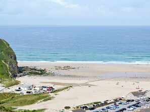 A coastal view with a beach, parking area, and buildings. - 2 bedroom accommodation in Mount Hawke, near Redruth (Mount Hawke, near Redruth)