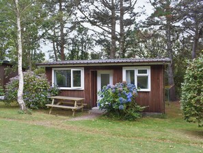 A small wooden cabin with a single window, a door, and a bench outside. - 2 bedroom accommodation in Mount Hawke, near Redruth (Mount Hawke, near Redruth)