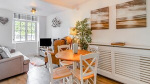 Un salon moderne comprenant un coin repas, un canapé, un téléviseur et des œuvres d’art accrochées aux murs.