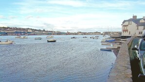 Un port où des bateaux sont amarrés le long de la rive, un mur de pierre et des bâtiments en arrière-plan.