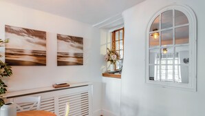A room with a white radiator, a wooden table with a vase, and a window with a light fixture.