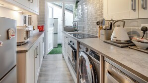 A modern kitchen with a built-in washing machine, a sink, and a countertop with kitchen utensils.