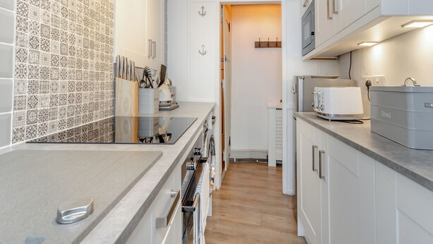 Une cuisine moderne avec des meubles blancs, un pare-feu en carrelage et un plancher en bois.